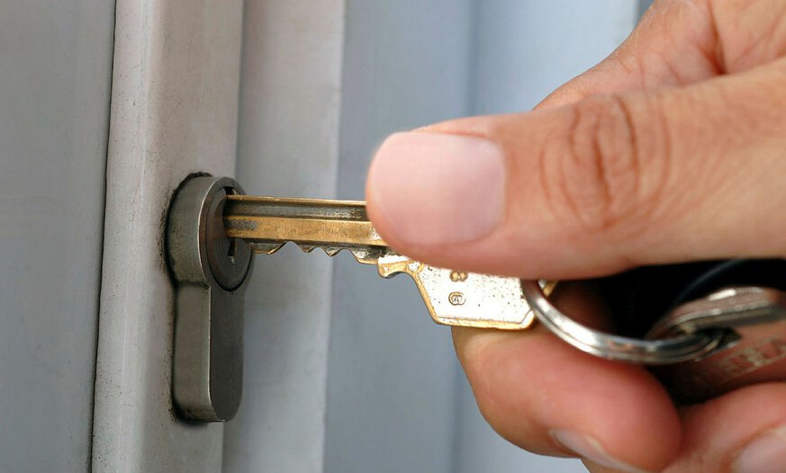 Hand steckt Schlüssel in Haustür